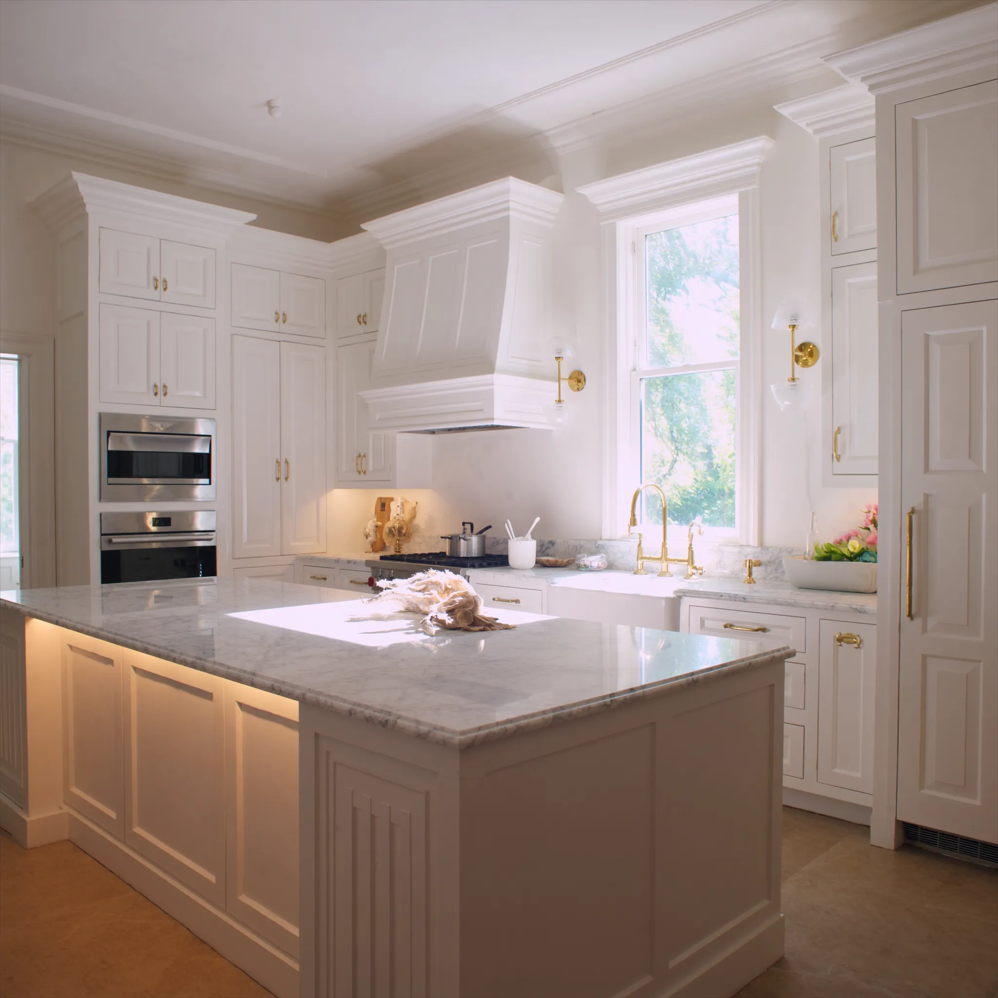 Sparkling clean white coastal kitchen with marble island and brass fixtures